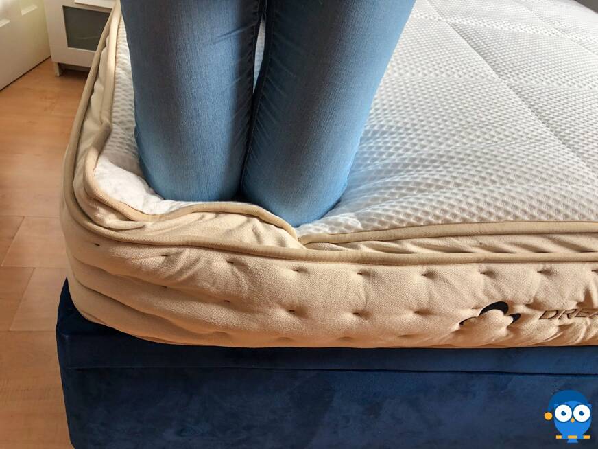 Kneeling on the edge of the DreamCloud mattress